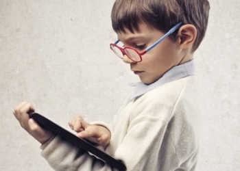 Child with glasses using a laptop computer