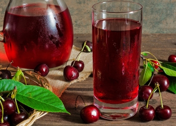 cold cherry juice in a glass and pitcher on wooden table with ripe berries in wicker basket; Shutterstock ID 447393178; Purchase Order: -